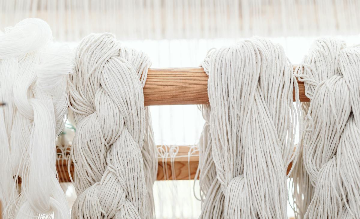 Primo piano di un intreccio in macramè con nodi decorativi su corda di cotone bianca, in stile artigianale boho