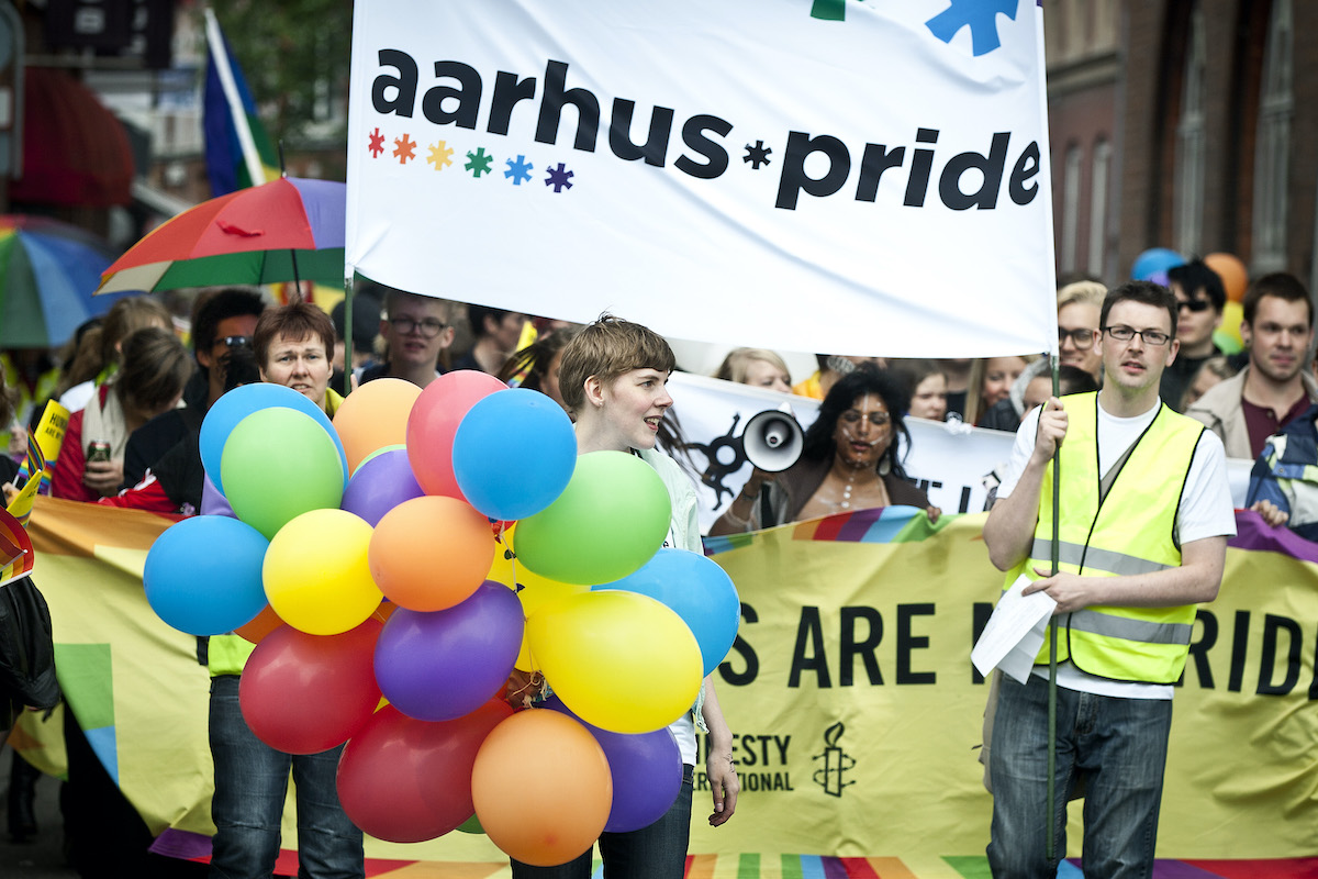 Parata dell'Aarhus Pride con bandiere arcobaleno e persone che sfilano nel centro storico della città, simbolo del turismo LGBTQ+ in Danimarca